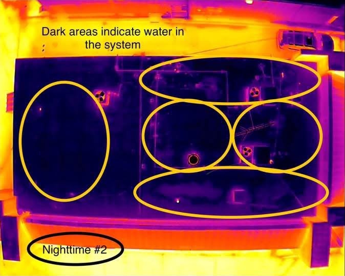 Thermal image of a flat roof at night, with circled dark zones marking water trapped in the roof system
