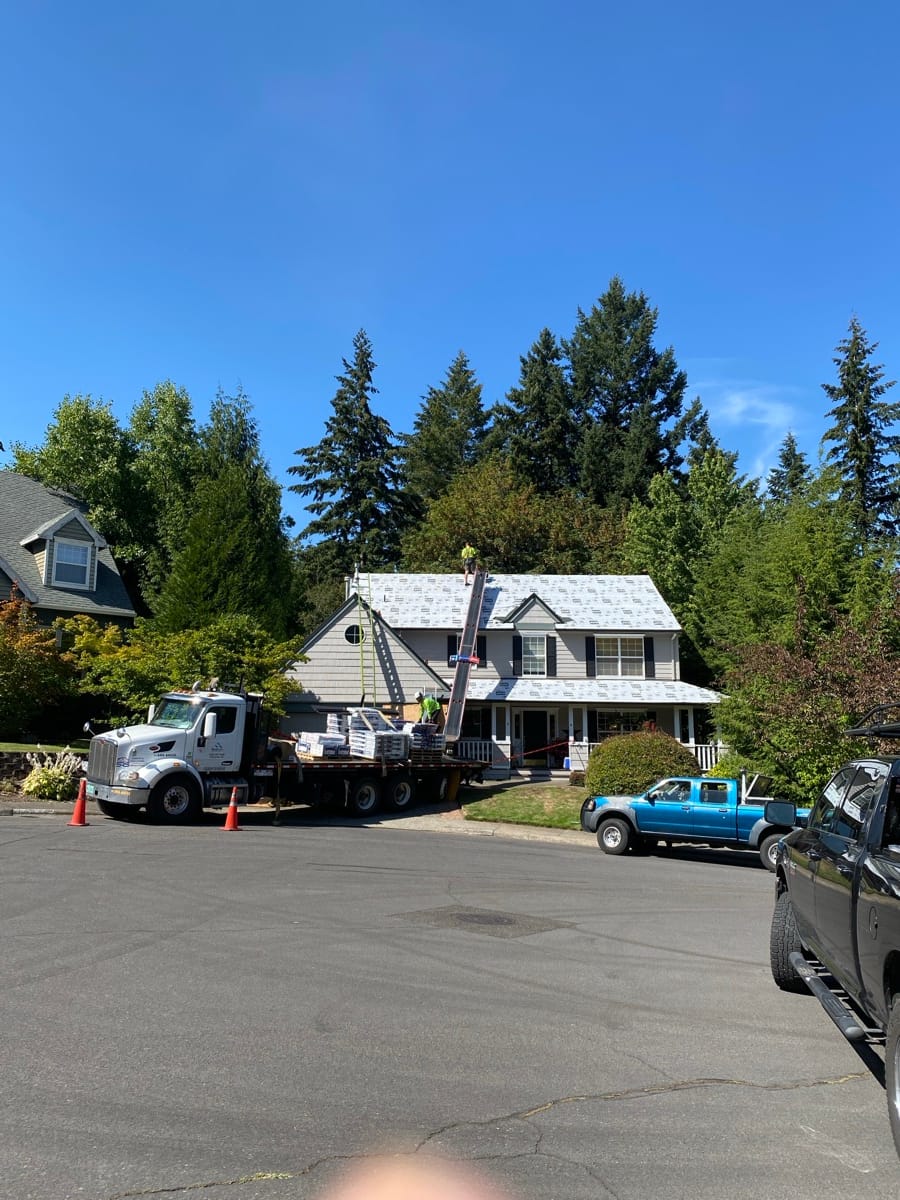 Boom truck lifting roofing material up to a roof