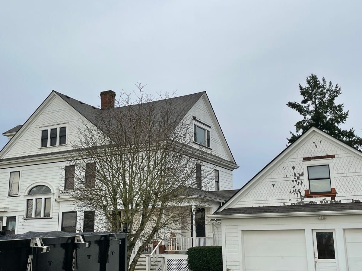Job site with dumpster and truck in the driveway