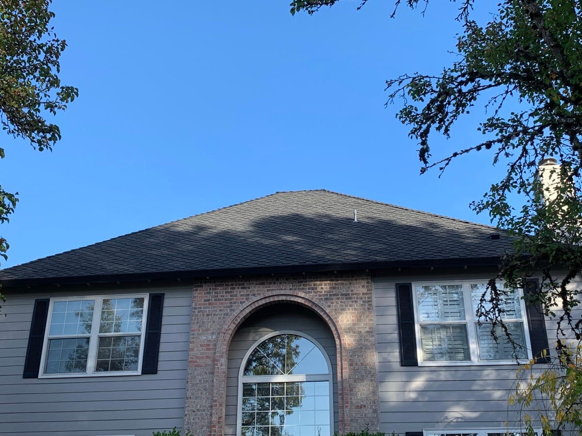 Brick home with an arched entry and a new dark shingle roof