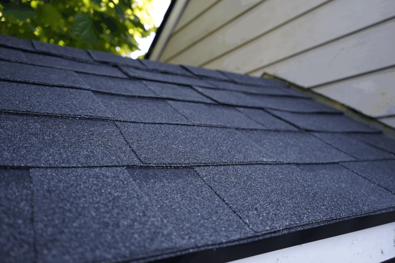 The same porch roof with new black shingles and a black drip edge along the eave
