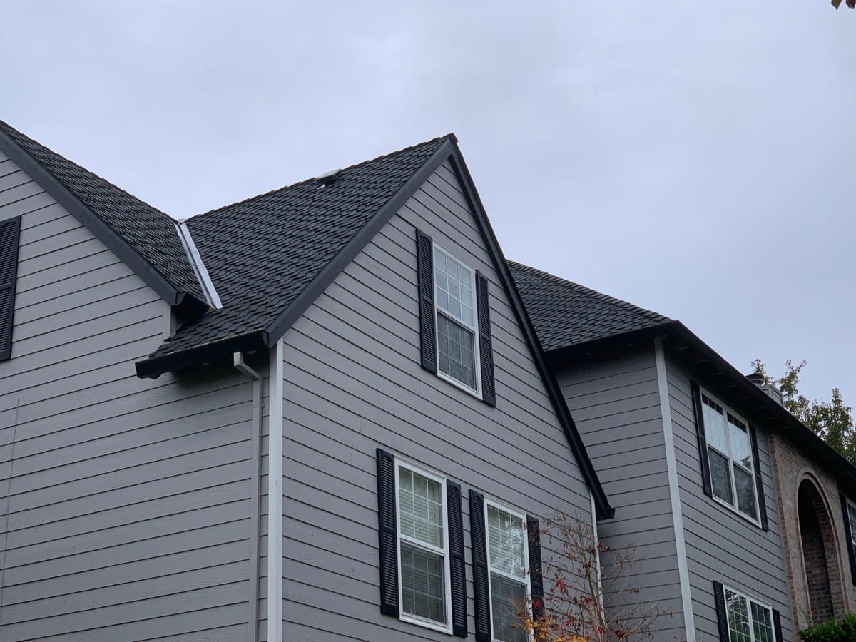 Gray home with new shingles across two gables